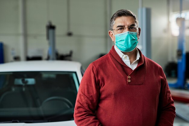 Portrait of mid adult man with protective face mask in auto repair shop