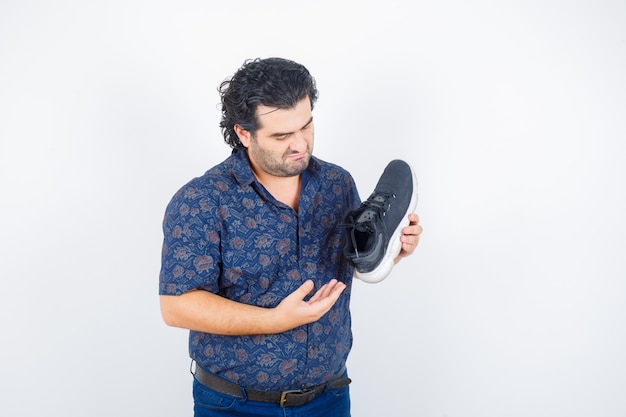 Free photo portrait of middle aged man presenting shoe in shirt and looking serious front view