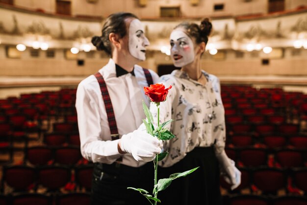 Portrait of mime couple holding red rose in the auditorium