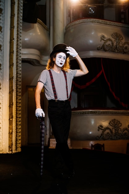 Portrait of mime male artist posing with umbrella on stage