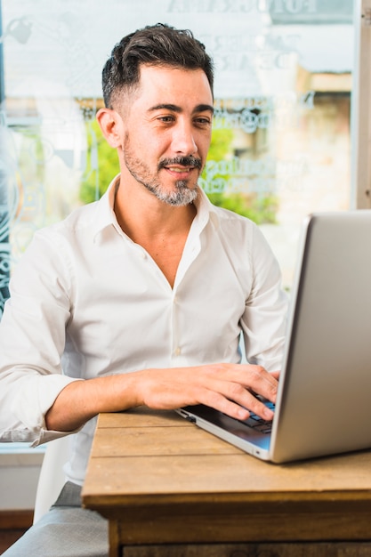 Portrait of a modern man sitting in cafe using laptop