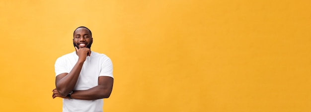 Portrait of a modern young black man smiling with arms crossed on isolated yellow background