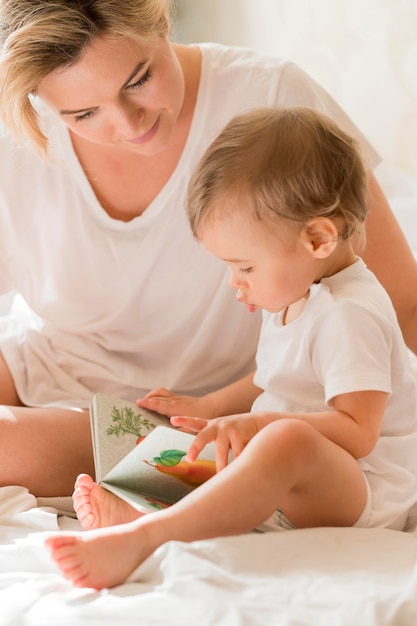 Portrait of mom reading to baby in bed