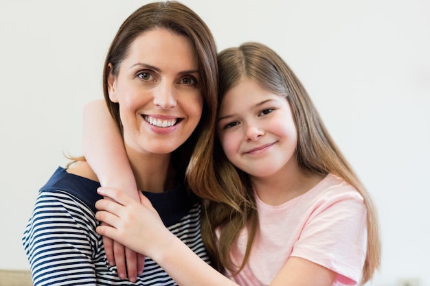 Portrait of mother and daughter embracing each other in living r