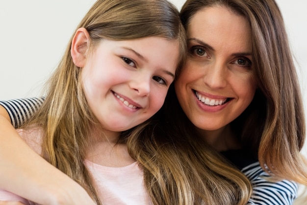 Portrait of mother and daughter embracing each other in living r