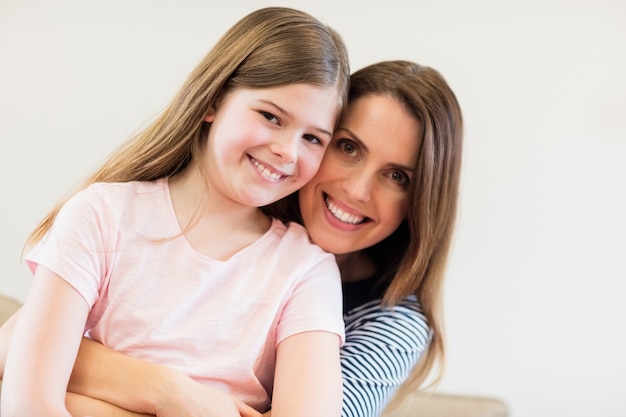 Portrait of mother and daughter embracing each other in living r