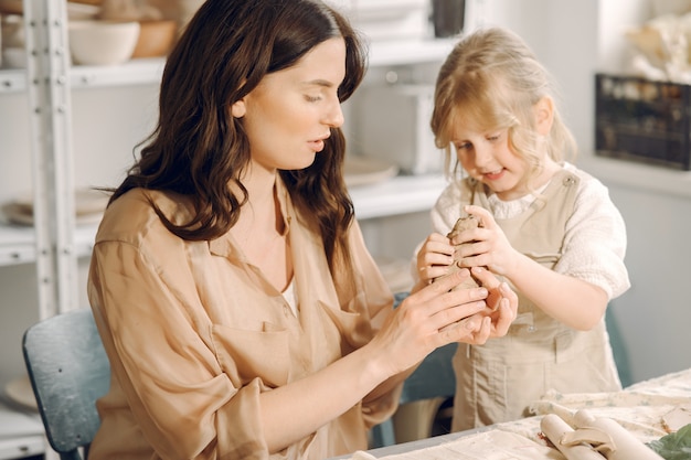 Portrait of mother and little girl shaping clay together