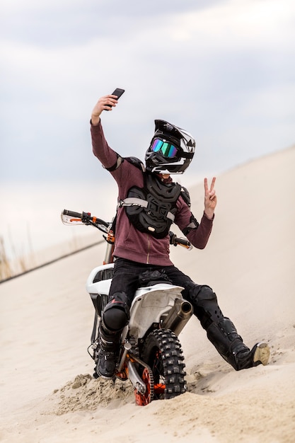 Free photo portrait of motorbike rider taking a selfie in the desert