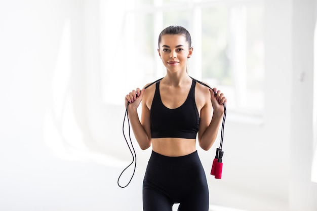 Portrait of muscular young woman exercising with jumping rope on white background