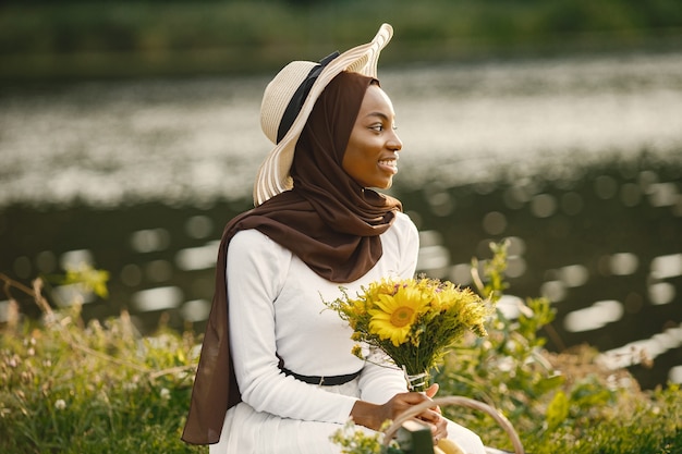 Portrait of a muslim woman sits on the plaid picnic blanket near the river