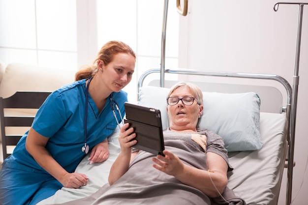 Free Photo portrait of old woman in nursing home using tablet computer. female nurse with retired woman.