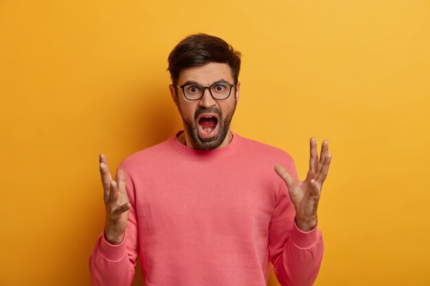 Free photo portrait of outraged man stands in furious gesture, screams loudly