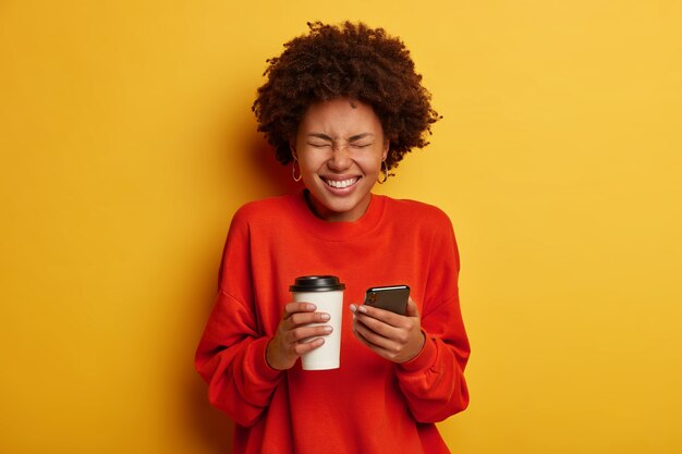 Portrait of overjoyed African American woman makes notes in smartphone