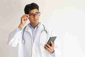 Free photo portrait of pensive doctor with smartphone