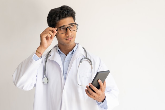 Portrait of pensive doctor with smartphone