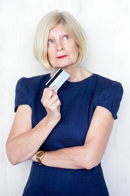 Portrait of pensive senior woman with credit card