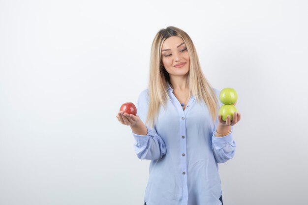 Portrait photo of a pretty attractive woman model standing and holding fresh apples .