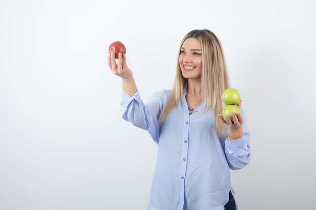 Portrait photo of a pretty attractive woman model standing and holding fresh apples .