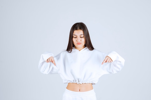 Portrait photo of a young girl model pointing down.