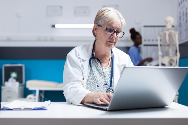 Portrait of physician with stethoscope using laptop to work on healthcare at clinic. Woman doctor working with computer and technology to do prescription treatment analysis for examination.