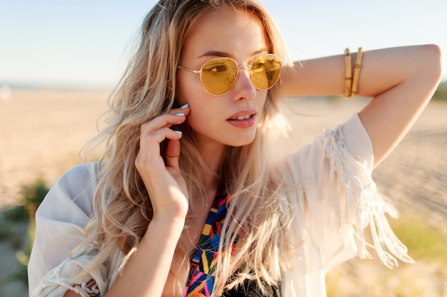 Portrait of playful smiling  blonde girl playing with hairs, having fun and enjoying summer on the beach .