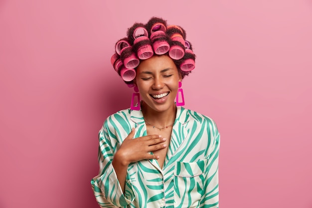 Portrait of pleasant looking young wearing hair curlers and casual silk dressing gown