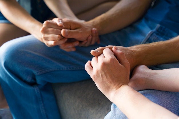 Portrait of polyamorous couple at home holding hands