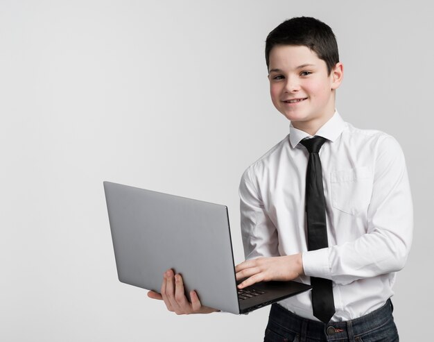 Portrait of positive young boy holding laptop