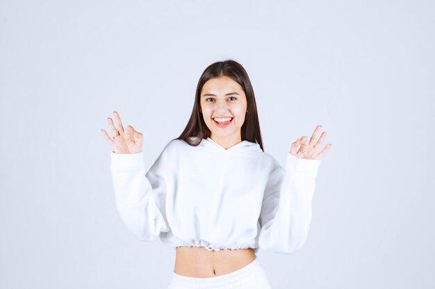 Portrait of a positive young girl showing ok gesture.