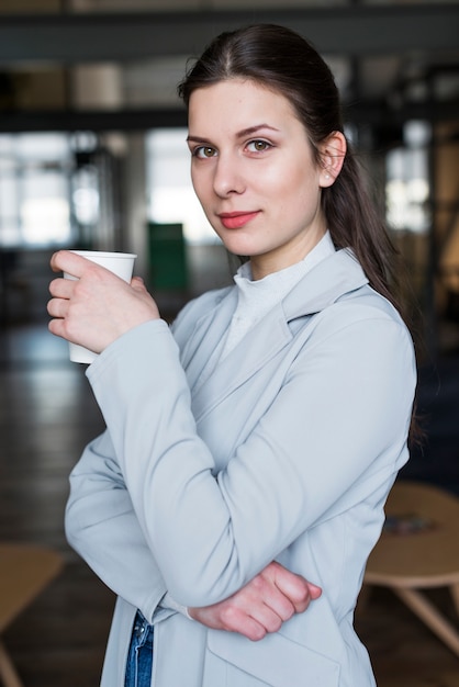 Portrait of pretty businesswoman holding coffee cup