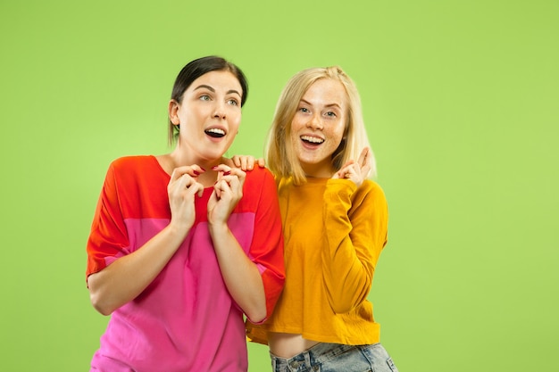 Portrait of pretty charming girls in casual outfits isolated on green studio wall