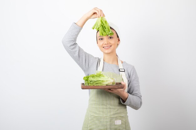 Portrait of a pretty cute woman holding a wooden board with fresh lettuce 