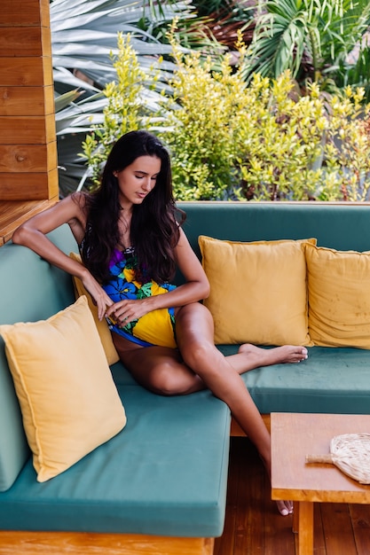 Free photo portrait of pretty fit slim positive woman resting with pillow at home on summer outdoor sofa, enjoying time alone