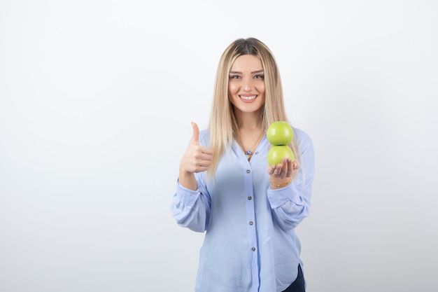 Free Photo portrait of a pretty girl model holding fresh apples and showing a thumb up.