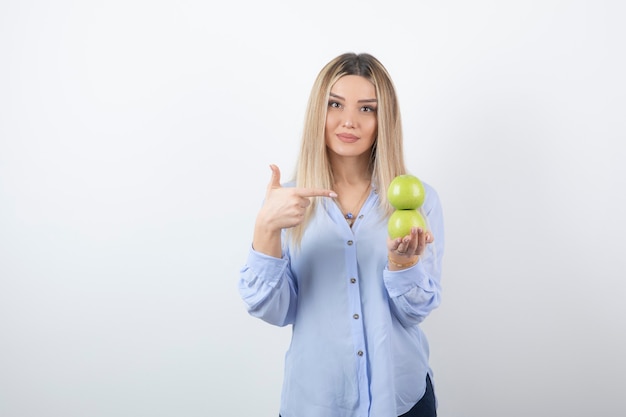 Free photo portrait of a pretty girl model pointing at fresh apples.