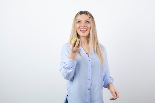 portrait of a pretty girl model standing and holding a green fresh apple.