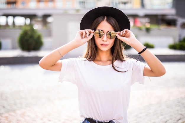 Portrait of a pretty girl in sunglasses and hat ioutdoors