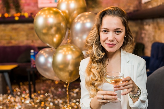 Portrait of a pretty smiling woman with glass of whiskey in party