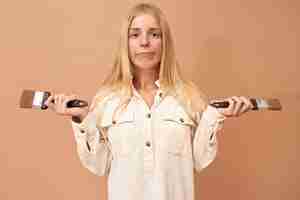 Free photo portrait of pretty teenage girl with braces and long hair using special tools while painting interior walls to protect them from damage by water or corrosion