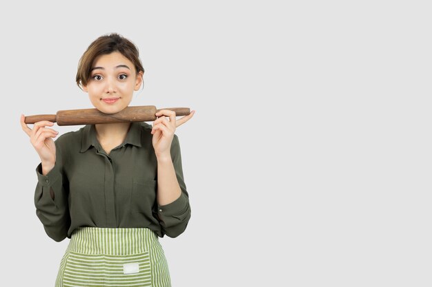 Portrait of pretty woman in apron holding a rolling pin