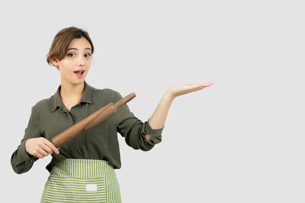 Portrait of pretty woman in apron holding a rolling pin