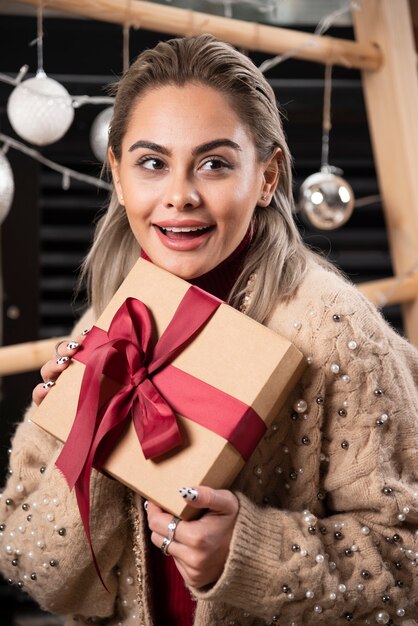 Portrait of pretty woman sitting and holding a Christmas present