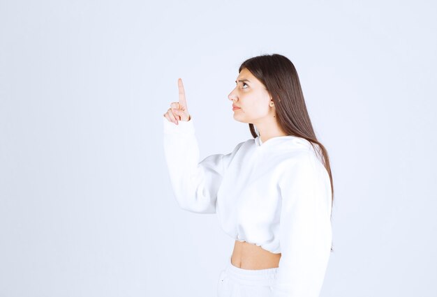 Portrait of pretty young girl model pointing up.