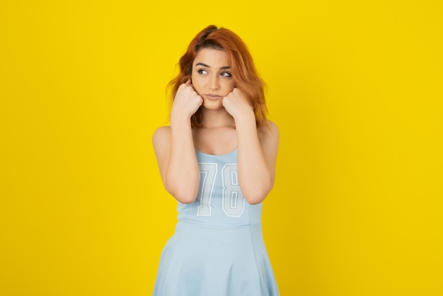 Portrait of Pretty young girl on yellow wall while looking away