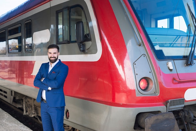 Free photo portrait of professional train driver standing by high speed train vehicle at station