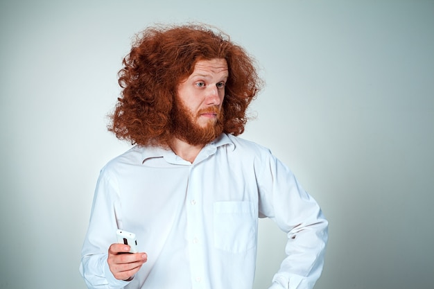 Portrait of puzzled man talking on the phone  a gray wall