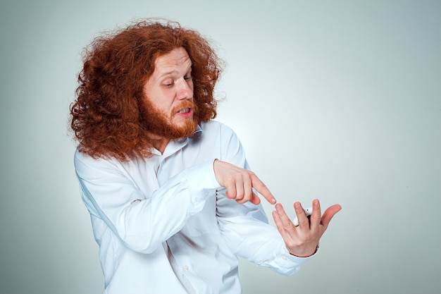 Free photo portrait of puzzled man with long red hair on a gray background