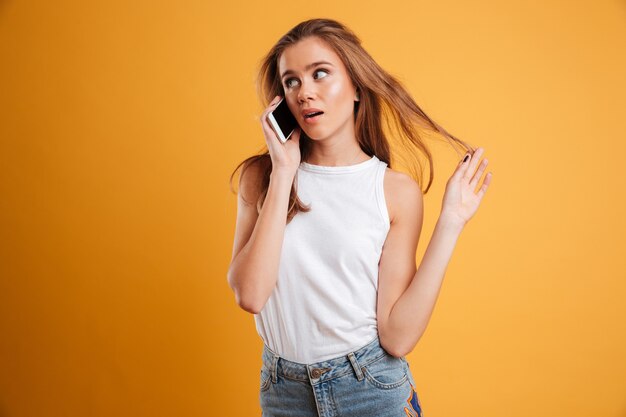 Portrait of a puzzled pretty girl talking on mobile phone