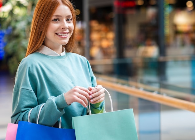 Free photo portrait of redhead woman holding shopping bags