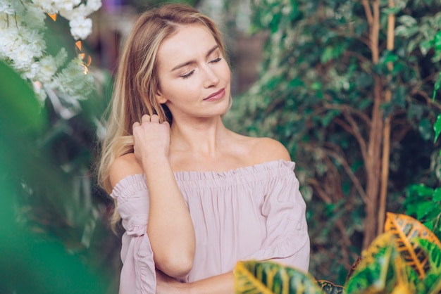 Portrait of relaxed young woman standing among the green plants